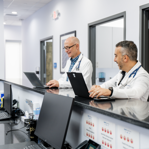 Dr. Aziz and Dr. Brown talking at the Nurses Station at ApexMed Primary Care