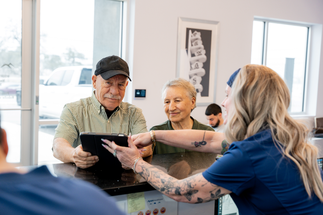 Patients checking in for an appointment at front desk with ApexMed Primary Care staff