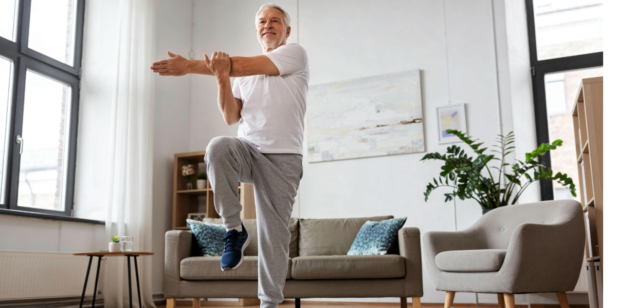 Image of a man over 55 doing a balance exercise in his home